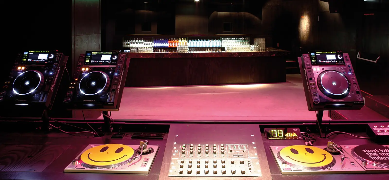 Two CDJs and a mixer in a dark club booth