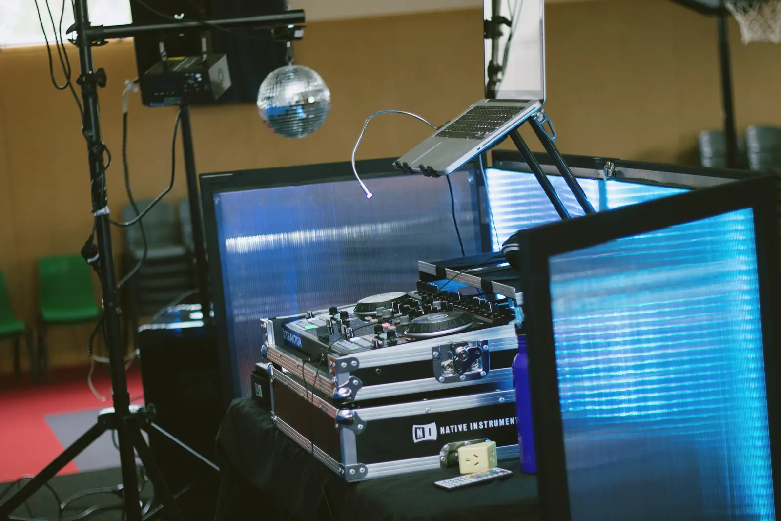 A home DJ booth with a controller, laptop and disco ball