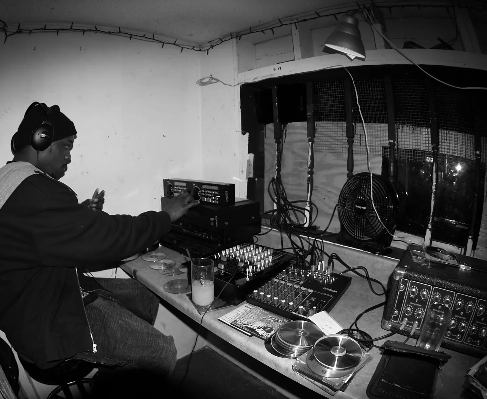 A DJ in headphones playing in a small, cluttered room