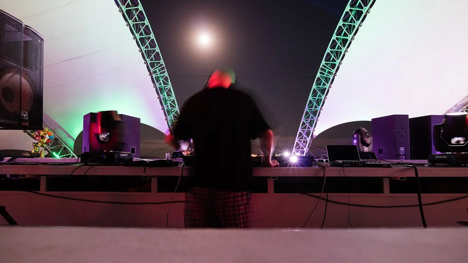 A DJ playing to a packed dance floor under coloured lights